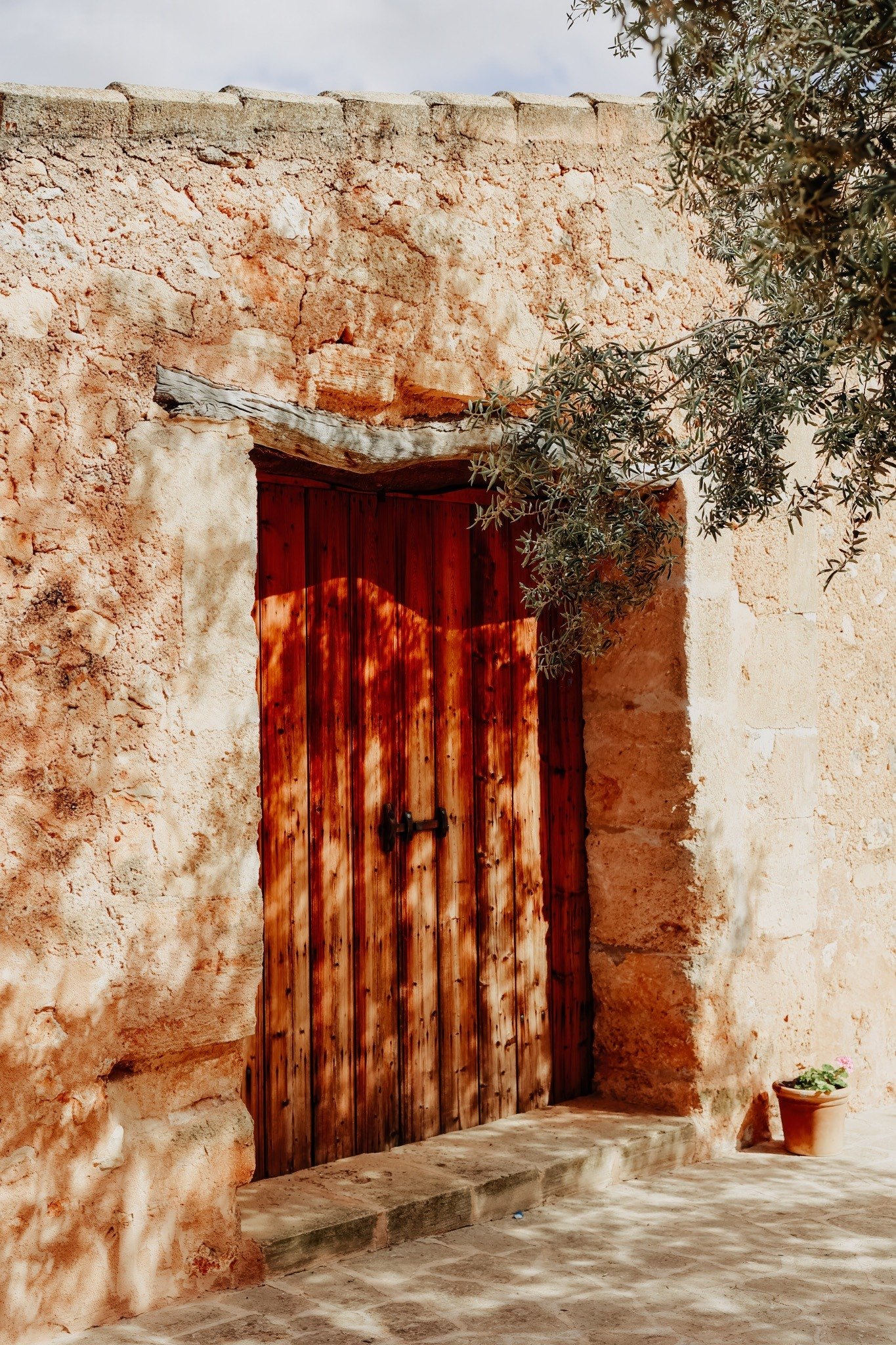Puerta tradicional de piedra mallorquina bajo un olivo